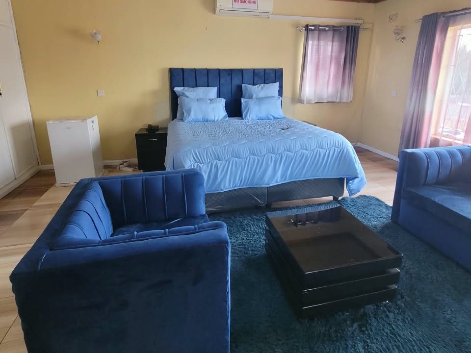 Executive Room with king bed and velvet lounge suite at Afro Lodges & Motels, Borrowdale, Harare